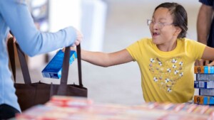 una niña donando cajas de macarrones con queso